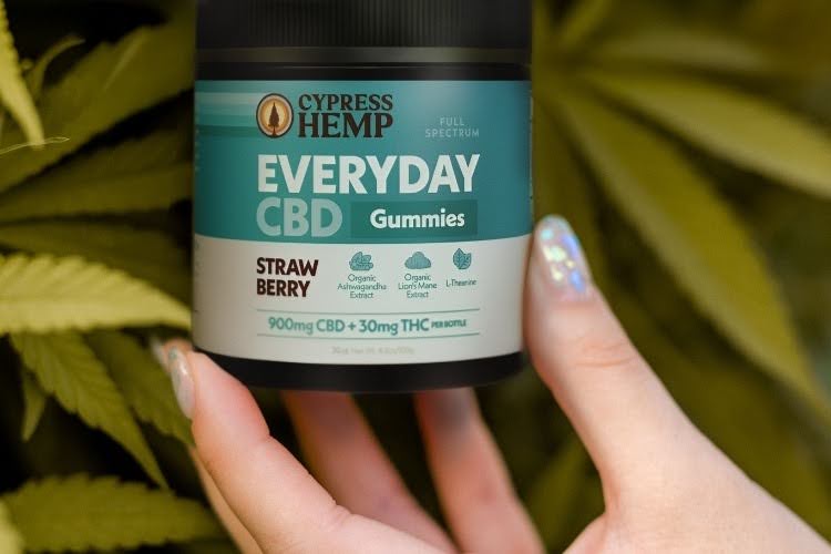 Full spectrum CBD gummies held in front of hemp leaves.
