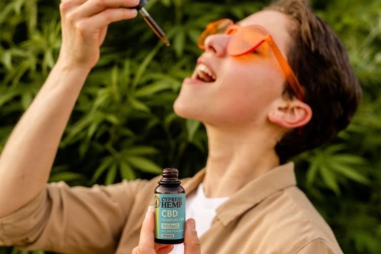 Person using full spectrum CBD oil with a dropper.